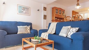 Un salon avec deux canapés bleus, une table basse en verre et un meuble en bois.