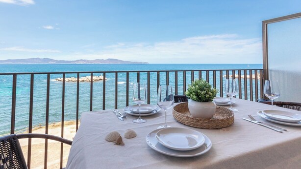 Une table dressée pour le dîner, avec vue sur la mer et les montagnes au loin.