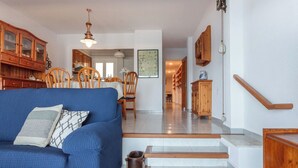 Un salon avec un canapé bleu, des meubles en bois et un escalier.