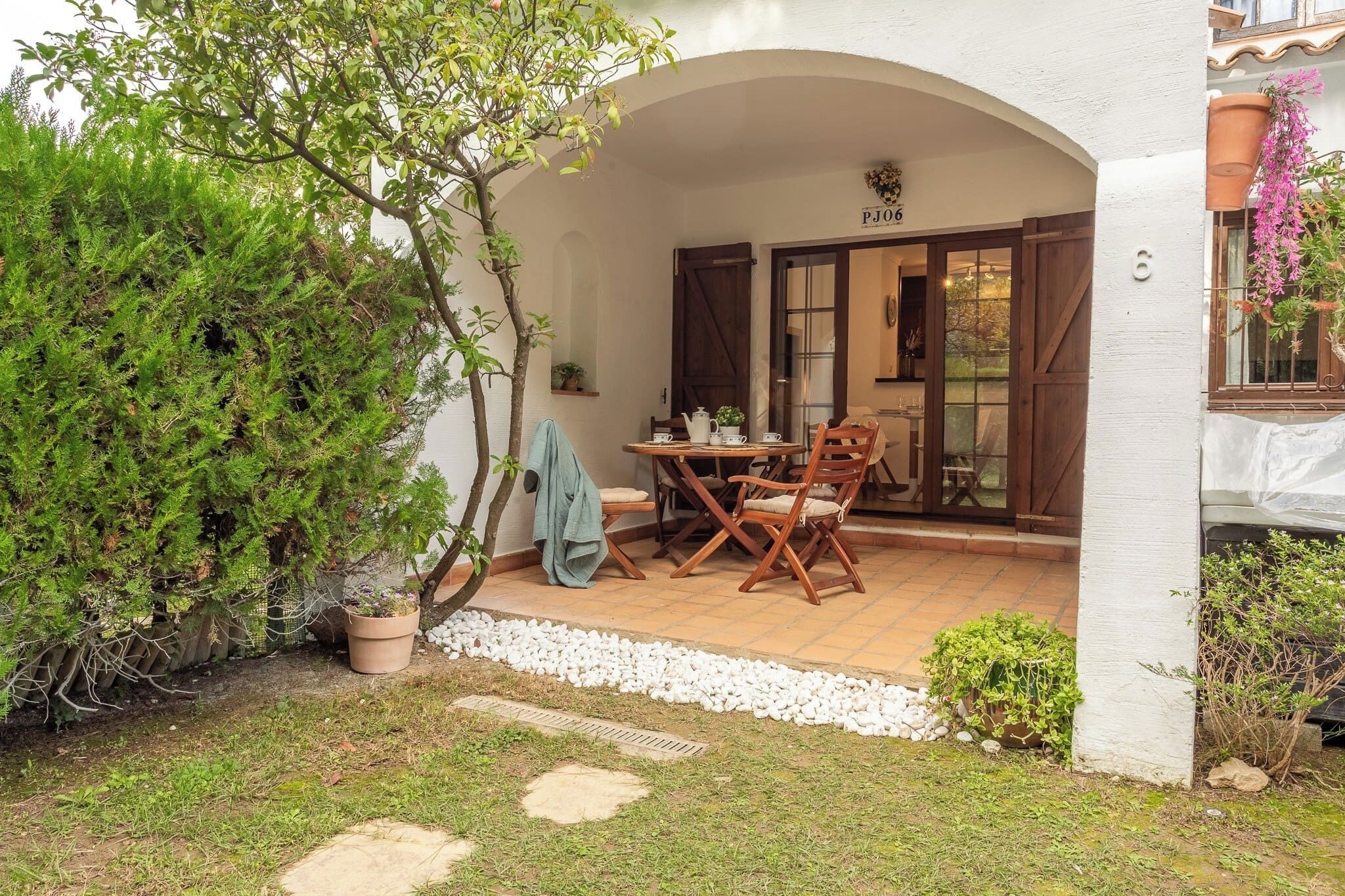 A patio with a table and chairs, a potted plant, and a door with a number.