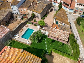 An aerial view of a courtyard with a swimming pool surrounded by buildings with terracotta roofs.