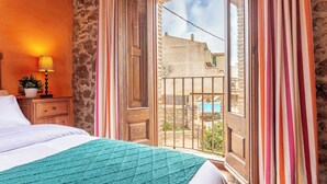 A bedroom with a bed, a nightstand with a lamp, and a view of a swimming pool through a window with curtains. - Rural House Salvador XVIII (La Tallada d'Empordà)