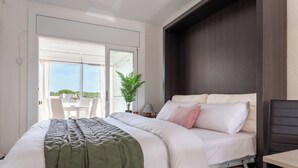 Ein modernes Schlafzimmer mit einem großen Bett, einem kleinen Tisch, einem Stuhl und einer Topfpflanze.