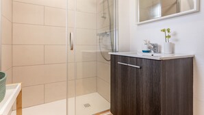 Une salle de bain moderne avec une douche à parois de verre, un meuble en bois et un lavabo blanc.