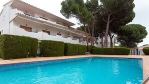 Une piscine à l’eau d’un bleu cristallin, entourée de haies soigneusement taillées et de grands arbres.
