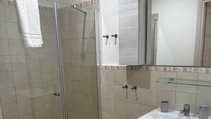 A bathroom with a glass shower enclosure, a white sink, and a mirror above it. - Double Room with private bathroom for the disabled in Terralba (Oristano) – Olivo (Terralba)
