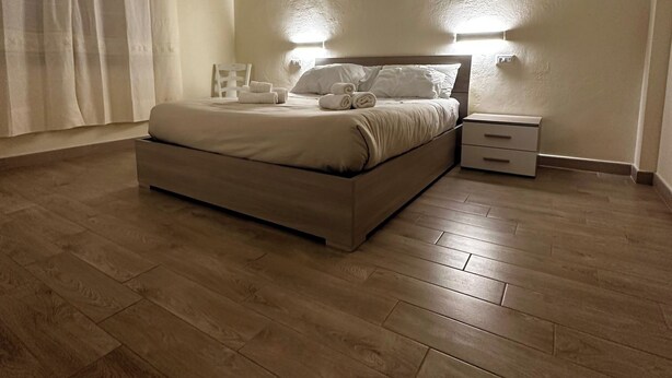A bedroom with a bed, bedside tables, and a window with curtains. - Double Room with private bathroom for the disabled in Terralba (Oristano) – Olivo (Terralba)
