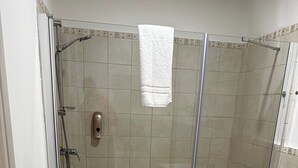 A shower area with a glass door, a white towel hanging on the wall, and a small white trash bin. - Double Room with private bathroom for the disabled in Terralba (Oristano) – Olivo (Terralba)