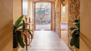 A hallway with tiled flooring, a wooden chair, and potted plants.