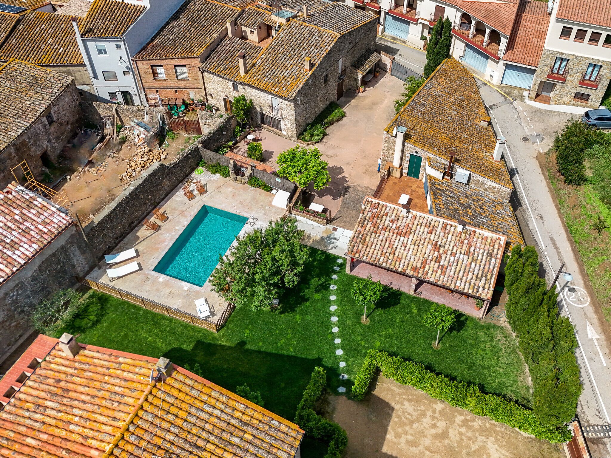 An aerial view of a courtyard with a swimming pool surrounded by buildings with terracotta roofs.