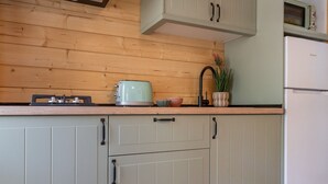 A kitchen with wooden paneling, a toaster, a sink, and a refrigerator. - Bungalow Forest (L'Escala)