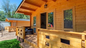 A wooden cabin with a covered porch, large windows, and a view of the surrounding forest. - Bungalow Forest (L'Escala)