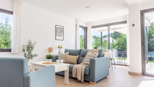 Un salon moderne avec un canapé gris, une table basse blanche et une plante.