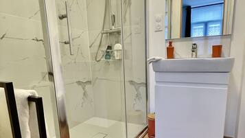 Une salle de bain moderne avec une douche à parois de verre, un lavabo blanc et un miroir au-dessus.
