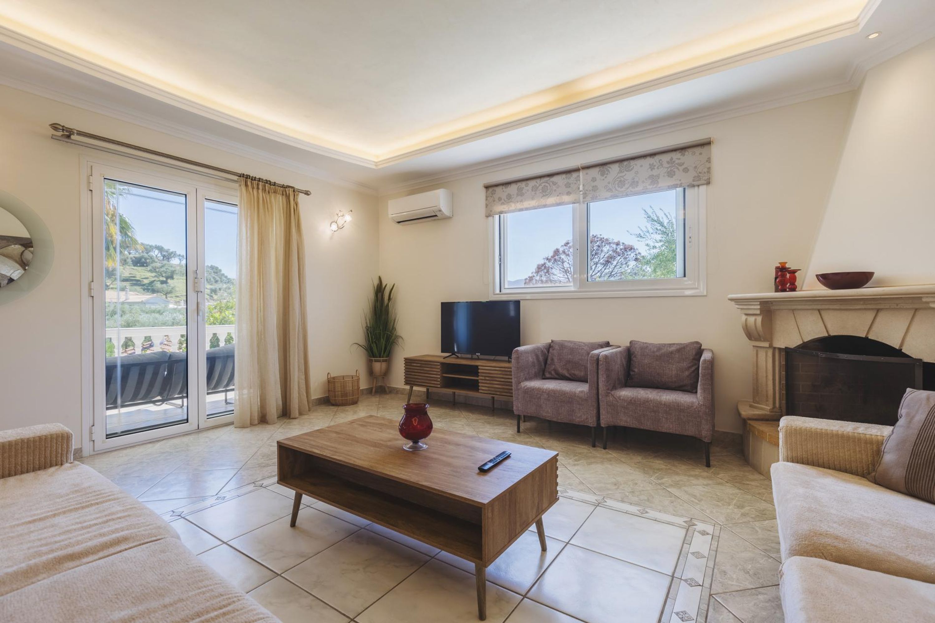 A living room with a sofa, a coffee table, a TV, and a fireplace.