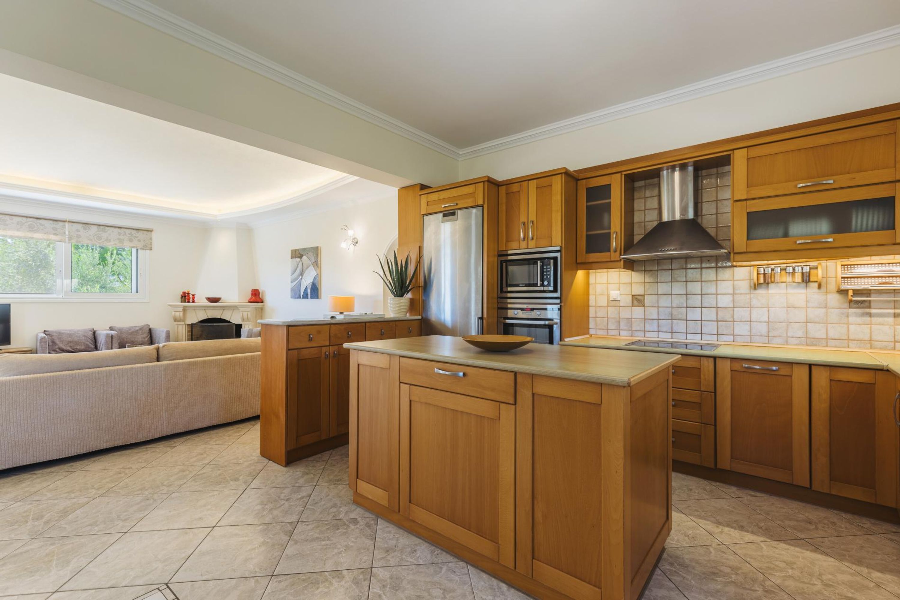 A modern kitchen with wooden cabinets, stainless steel appliances, and a large island.