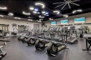 Un gimnasio con cintas de correr, elípticas y equipo de pesas.