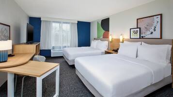A hotel room with two beds, a desk, a TV, and a window with curtains.
