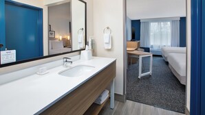 A modern hotel bathroom with a large mirror, two sinks, and a shower area. - Spark By Hilton Walker Grand Rapids North (Grand Rapids)