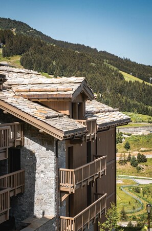 A stone building with wooden balconies and a sloped roof. - Wifi, 150m from ski slopes, 2nd floor, view mountain, sauna, balcony, fireplace or stove, parking (Courchevel)