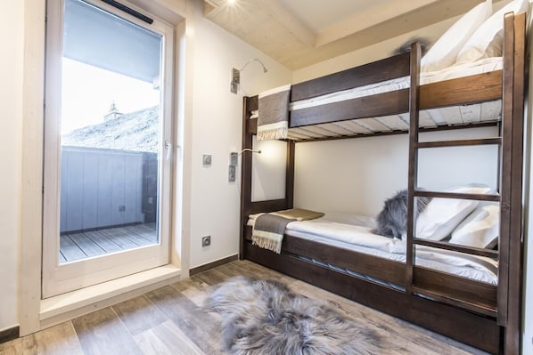 A bunk bed room with a sliding glass door leading to a balcony.