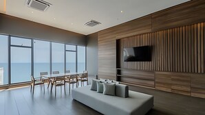 Una sala de estar moderna con un ventanal grande, un sofá y un televisor de pantalla plana montado en una pared de madera.
