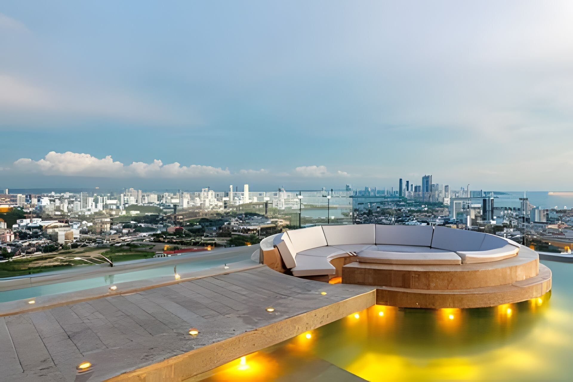 A rooftop pool area with a circular seating arrangement and a cityscape view in the background.