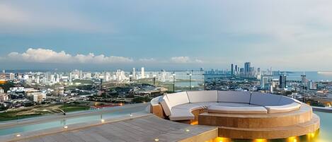A rooftop pool area with a circular seating arrangement and a cityscape view in the background.