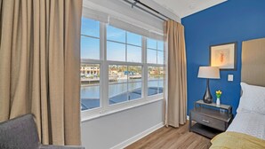 Una habitación de hotel con una ventana grande, una cama, una mesita de noche y una silla.