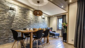 Un comedor con pared de piedra, una mesa de madera y sillas negras.