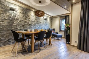 A dining area with a stone wall, a wooden table, and black chairs.