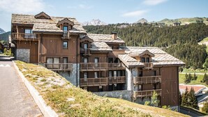 Un hotel de varios pisos con balcones de madera y un paisaje montañoso de fondo.
