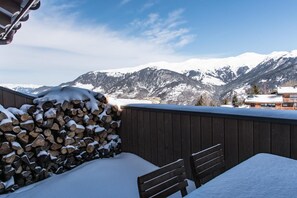 A wooden deck with a stack of firewood and a bench, overlooking snow-covered mountains. - Wifi, 200m from resort center, 5th floor, view exceptional/mountain, sauna, terrace, balcony (Courchevel)