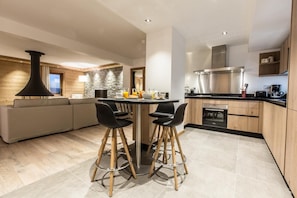 A modern kitchen with a central island, bar stools, a built-in oven, and a stone accent wall.