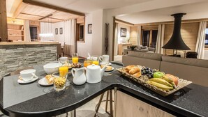 A modern kitchen with a central island, breakfast setup, and a cozy seating area with a fireplace. - Wifi, 150m from ski slopes, 2nd floor, view mountain, sauna, balcony, fireplace or stove, parking (Courchevel)