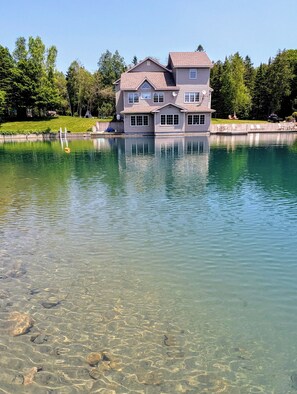 Ein zweistöckiges Haus mit einer großen Veranda und einem Swimmingpool im Vordergrund.