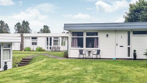 A row of white mobile homes with a grassy yard, a bench, and a table with chairs. - 2 bedroom accommodation in Roch, near Haverfordwest (Roch, near Haverfordwest)