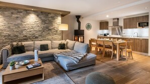 Un salon moderne avec un mur en pierre, une cheminée, un canapé, une table basse et un coin repas doté de meubles en bois.
