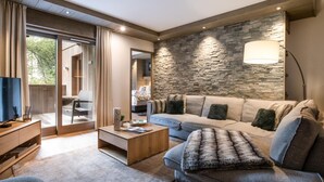 Un salon moderne avec un mur d’accent en pierre, un grand canapé, une table basse et un téléviseur posé sur un meuble en bois.