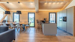 A modern kitchen with wooden cabinets, a central island, and a dining area with a table and chairs. - Superior Holiday Home With Sauna (Haus)