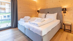 A modern bedroom with a large bed, two bedside tables, and a view of the outdoors. - Superior Holiday Home With Sauna (Haus)