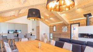 A modern interior with a wooden dining table, grey upholstered chairs, a sofa, and a fireplace. - Superior Holiday Home With Sauna (Haus)