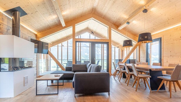 A spacious loft-style room with a large window, a fireplace, a dining area, and a cozy seating area. - Superior Holiday Home With Sauna (Haus)