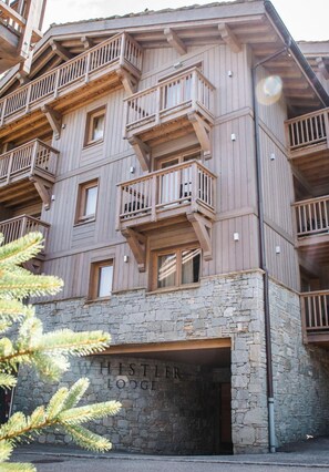 A multi-story wooden building with balconies and a stone entrance labeled "Hestler Lodge."