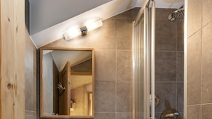 Une salle de bain moderne avec un meuble-lavabo en bois, un grand miroir et une douche à parois de verre.