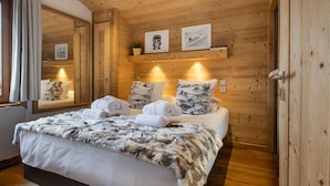 Une chambre aux murs lambrissés, avec un lit, des serviettes et des tableaux encadrés.