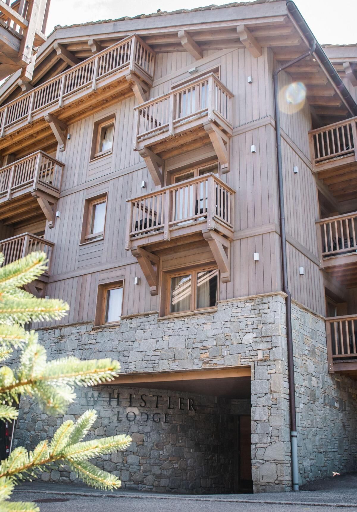 A multi-story wooden building with balconies and a stone entrance labeled "Hestler Lodge."