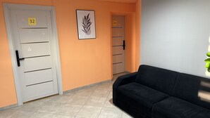 A hallway with doors numbered 32 and 33, a black couch, and a framed artwork on the wall. - Urban Rooms (Minsk)