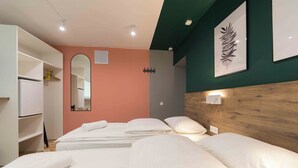 A hotel room with two beds, a wardrobe, a mirror, and a wall-mounted light fixture. - Urban Rooms (Minsk)