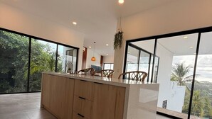 Una cocina moderna con una isla central, ventanas amplias y vistas al verdor.